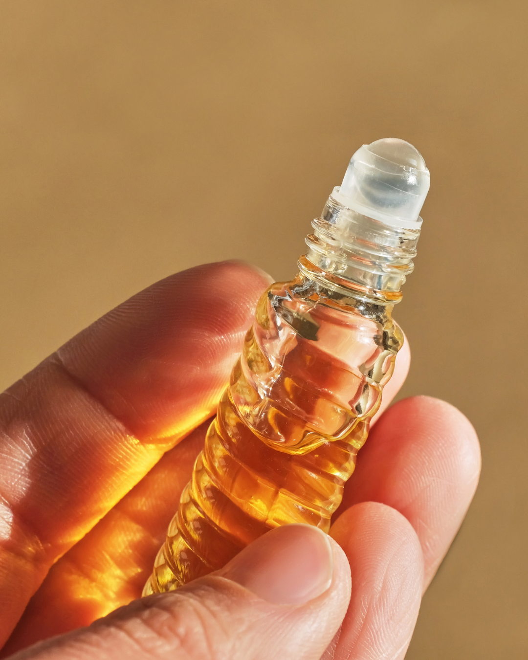 Perfume oil roller bottle with beige background 